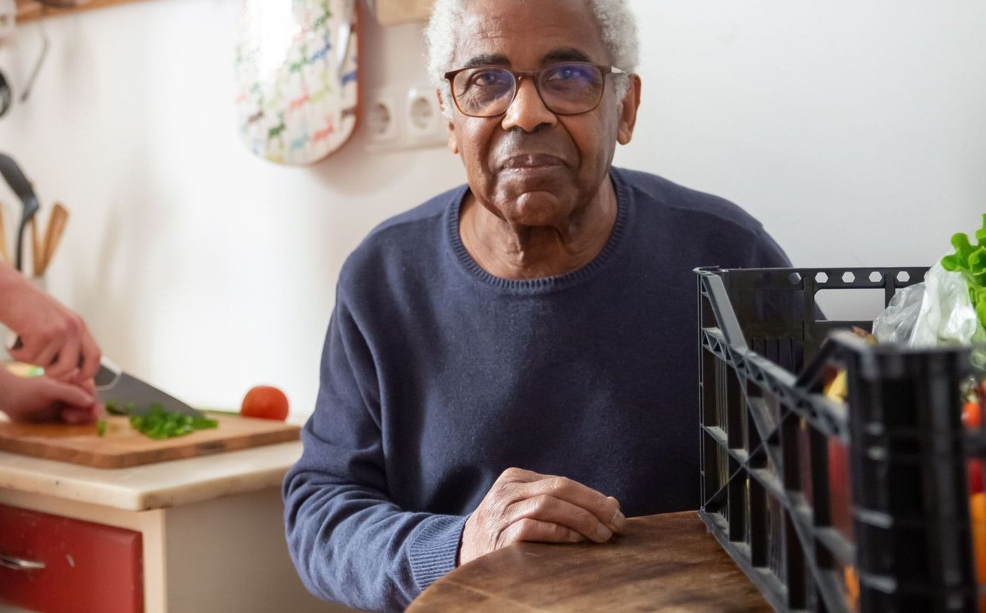 A young adult helping a senior in the kitchen, highlighting care and support at home.